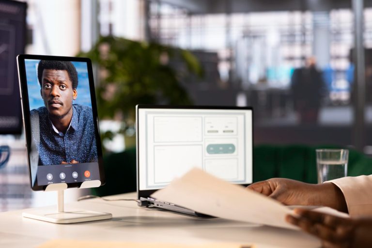 Un directeur d'entreprise utilise une tablette pour faire un appel vidéo avec le PDG pour discuter de la paperasserie.